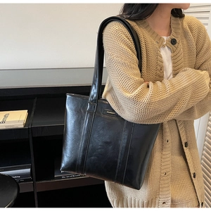 Sac fourre-tout classique en cuir noir avec logo porté dans un cadre lifestyle élégant