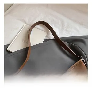 Detail of adjustable leather strap and silver hardware on floral embossed brown tote