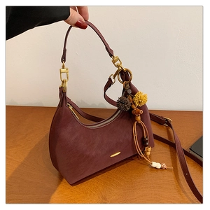 Detail of burgundy hobo bag with gold hardware and colorful ethnic tassel charms