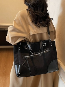 Large black vintage tote bag with rivets and metal rings shown on a model's shoulder