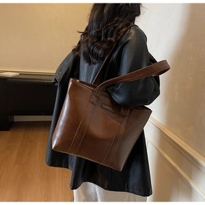 Vue détaillée du sac cabas en cuir marron brillant avec de longues bretelles pour le quotidien