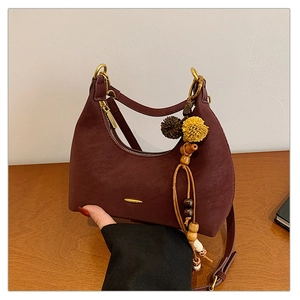 Close-up of wine red dumpling bag with litchi texture, gold hardware and floral charm