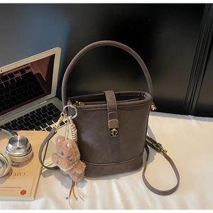 Détail du sac seau marron foncé avec boucle dorée et pendentif ours en peluche doux
