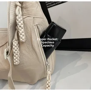 Detail view of beige nylon crossbody bag side zipper pocket with woven cord puller