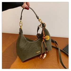 Detail of dark green suede hobo bag with wooden bead and yellow pompom charms