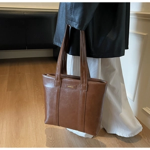 Sac fourre-tout en cuir marron avec logo métallique chic et détail de bandoulière élégant