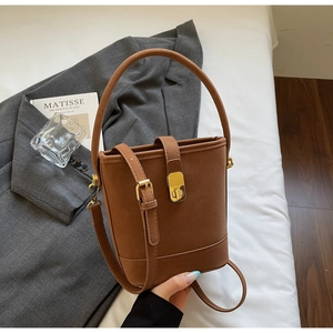 Détail du sac seau marron vintage avec fermoir doré et bandoulière réglable en situation