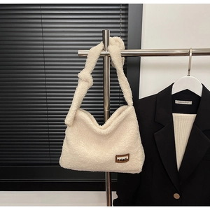 Detail of white plush hobo bag featuring a knotted shoulder strap and leather brand tag