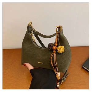 Detail of olive green crescent bag with matte texture and decorative beaded tassel