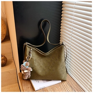 Detail of olive green hobo bag with floral embossing and a cute brown bear charm