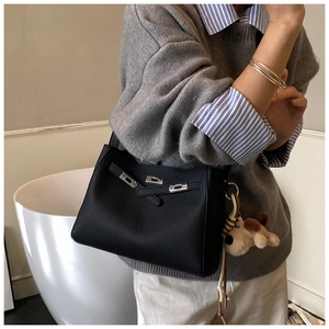 Close-up of black lychee leather bucket bag with silver rotating lock and puppy charm