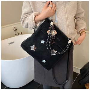 Détail d'un sac bandoulière noir mat avec patchwork d'étoiles et poignée tressée