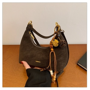 Close-up of dark brown suede crescent bag with gold hardware and colorful beaded tassel