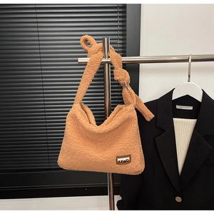 Detail of camel plush tote bag featuring a decorative knotted strap and brand label