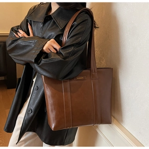Détail du grand sac cabas en cuir marron avec logo doré et larges bandoulières