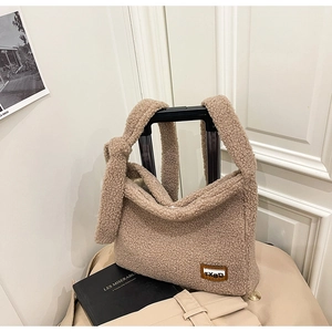 Detail of light camel sherpa fleece bag featuring a brown brand tag and knotted wide strap