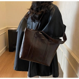 Vue détaillée du grand sac cabas marron foncé avec logo métallique porté par un mannequin
