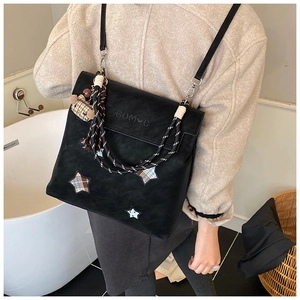 Détail du sac cabas en daim noir avec écusson étoile et poignées en corde tressée
