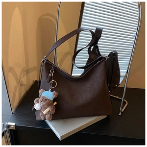 Detail view of dark brown embossed tote with silver buckle and cute bear charm pendant