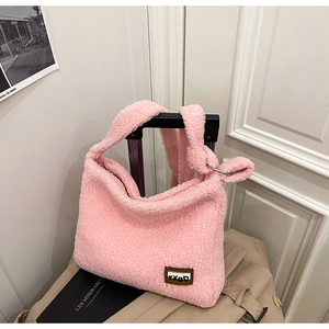 Detailed view of pink fleece tote bag with soft texture and logo tag on a suitcase