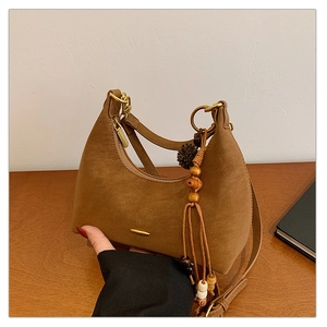 Close-up of brown suede hobo bag detailing with wooden beads and stylish tassel accents