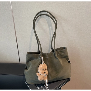 Close-up of olive green suede tote bag featuring white contrast stitching and puppy charm