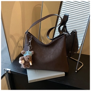 Macro view of vintage brown embossed tote bag with a cute plush bear charm accessory