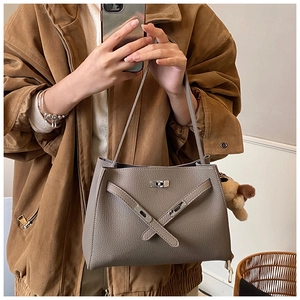 Detail of grey lychee leather handbag with silver lock and a cute plush charm