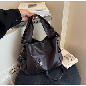 Close-up of coffee brown leather tote bag with functional zipper and metal lock detail