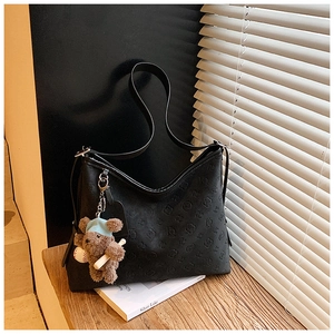 Close-up of black embossed leather tote bag with a zipper and cute teddy bear pendant