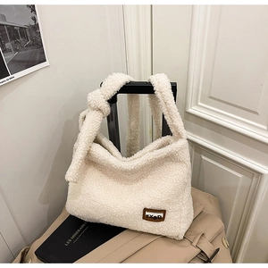 Close-up of off-white faux fur tote bag with leather logo tag and knotted shoulder strap