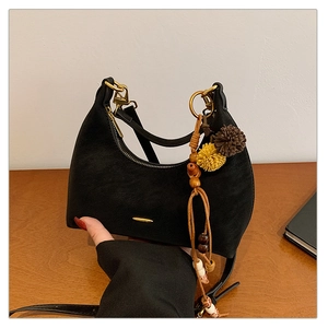 Detailed close-up of a black hobo dumpling bag with gold hardware and bohemian charms