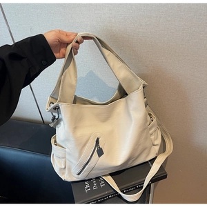 Detail of cream white faux leather tote with litchi texture and functional zip pockets