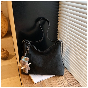 Detailed view of black embossed leather tote bag with cute brown bear charm