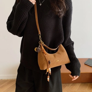 Detail of caramel brown hobo bag featuring matte faux leather and wooden beaded tassel charm