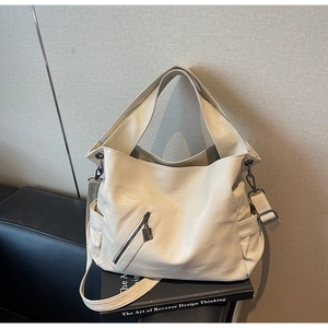 Close-up of cream white PU leather handbag with wide strap and detailed front zipper pocket
