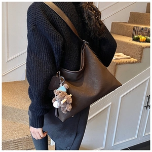 Detail of dark brown hobo bag featuring embossed texture and cute bear pendant accessory