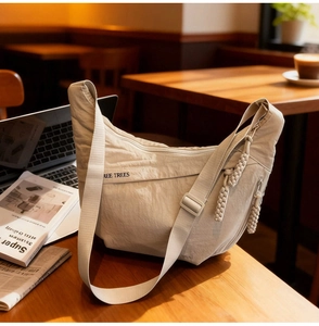 Detail of beige crescent nylon bag showing the woven zipper pull and REE TREES logo