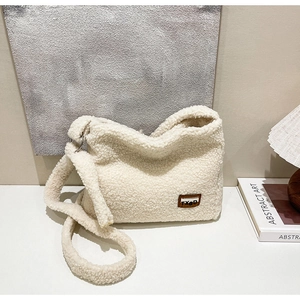 Detail of soft cream faux fur texture and brown leather label on the crossbody bag