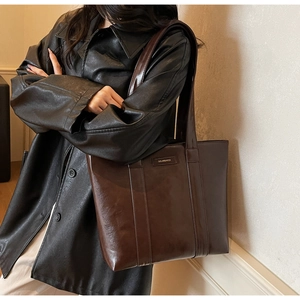 Détail d'un grand sac cabas en cuir marron foncé avec texture lisse et plaque Solaremiss