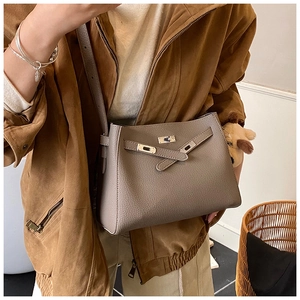 Detail view of taupe lychee texture leather crossbody bag with cute dog plush charm