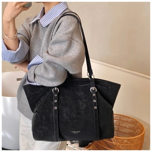 Détail du grand sac cabas noir en cuir avec œillets argentés et logo embossé