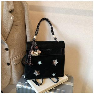 Détail du sac à dos noir mat avec écussons étoiles, motif à carreaux et breloque à pompon