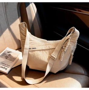 Detail of beige half-moon nylon crossbody bag with REE TREES logo on car leather seat