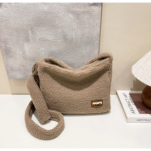 Close-up of brown fuzzy fleece texture and leather brand tag on the soft shoulder bag