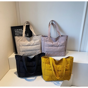 Quilted puffer tote bags in beige, purple, black, and yellow displayed on stairs