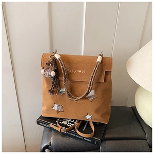 Détail d'un sac à dos marron mat avec broderie étoile et une poignée en corde tressée
