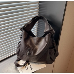 Detail of dark brown tote bag showing pebbled leather texture and front zipper pocket