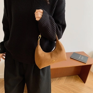 Close-up of brown suede hobo bag with gold hardware worn with a black knit sweater