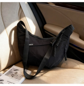 Detail of black nylon half-moon crossbody bag with TREES print on car leather seat